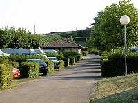 Vorschaubild: Camping Municipal la Grappe de Fleurie in Fleurie Vorn die abgegrenzten Stellplätze, im Hintergrund ein Sanitärgebäude, außerhalb die Weinberge