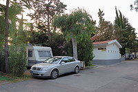 Vorschaubild: Camping Villággio Turistico la Mantinera in Práia a Mare Recht enger schattiger Stellplatz. Einfaches Sanitärgebäude im Hintergrund